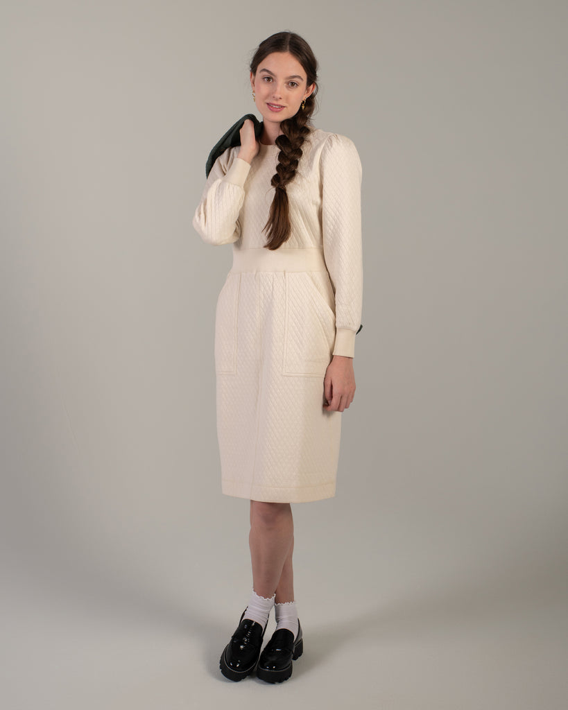 Woman in a white long sleeve, knee-length quilted dress