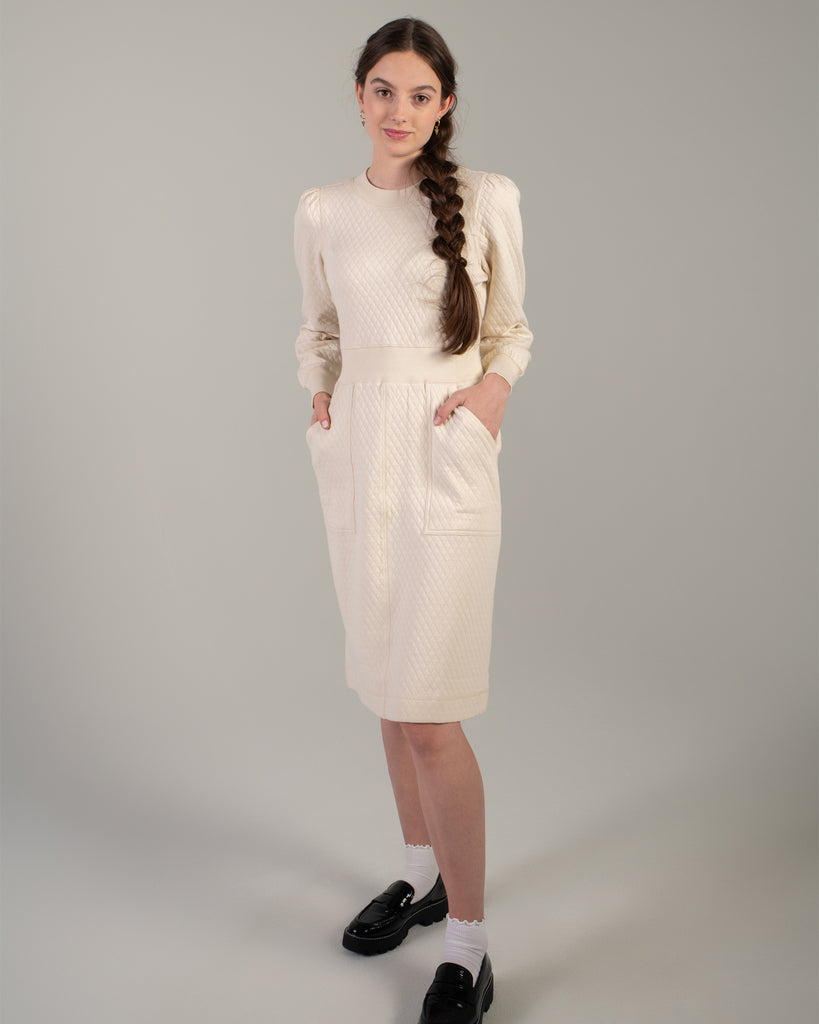 Woman in a white long sleeve, knee-length quilted dress