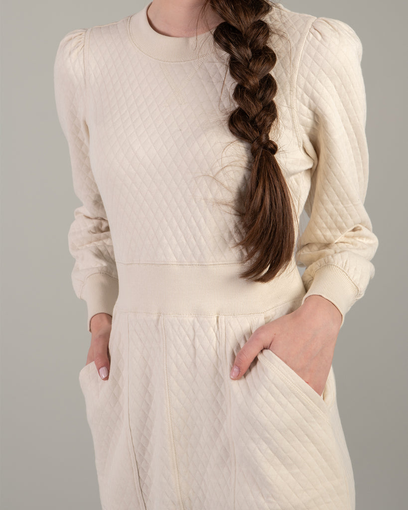 Woman in a white long sleeve, knee-length quilted dress