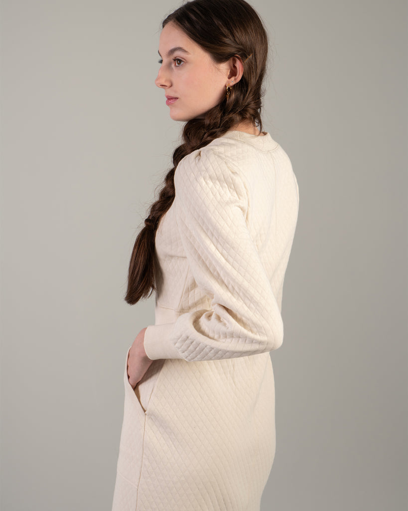 Woman in a white long sleeve, knee-length quilted dress