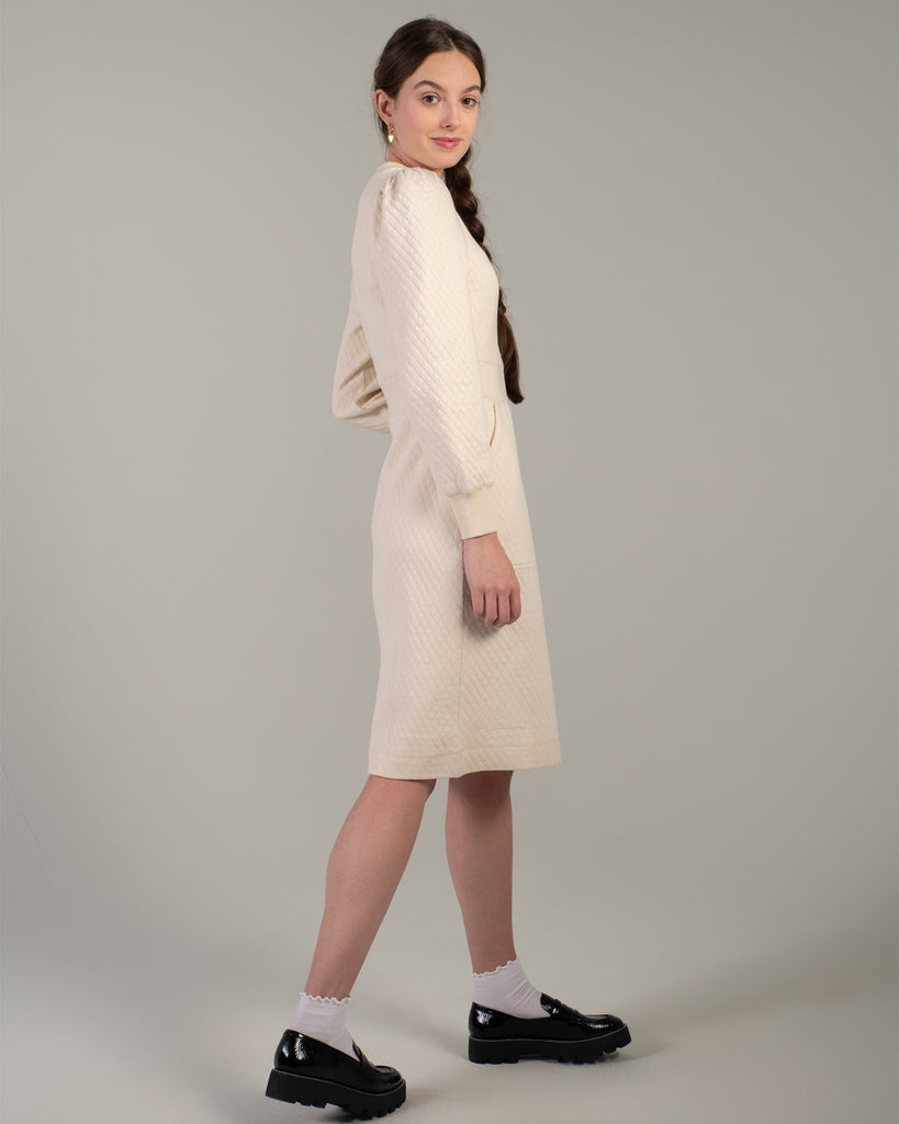 Woman in a white long sleeve, knee-length quilted dress