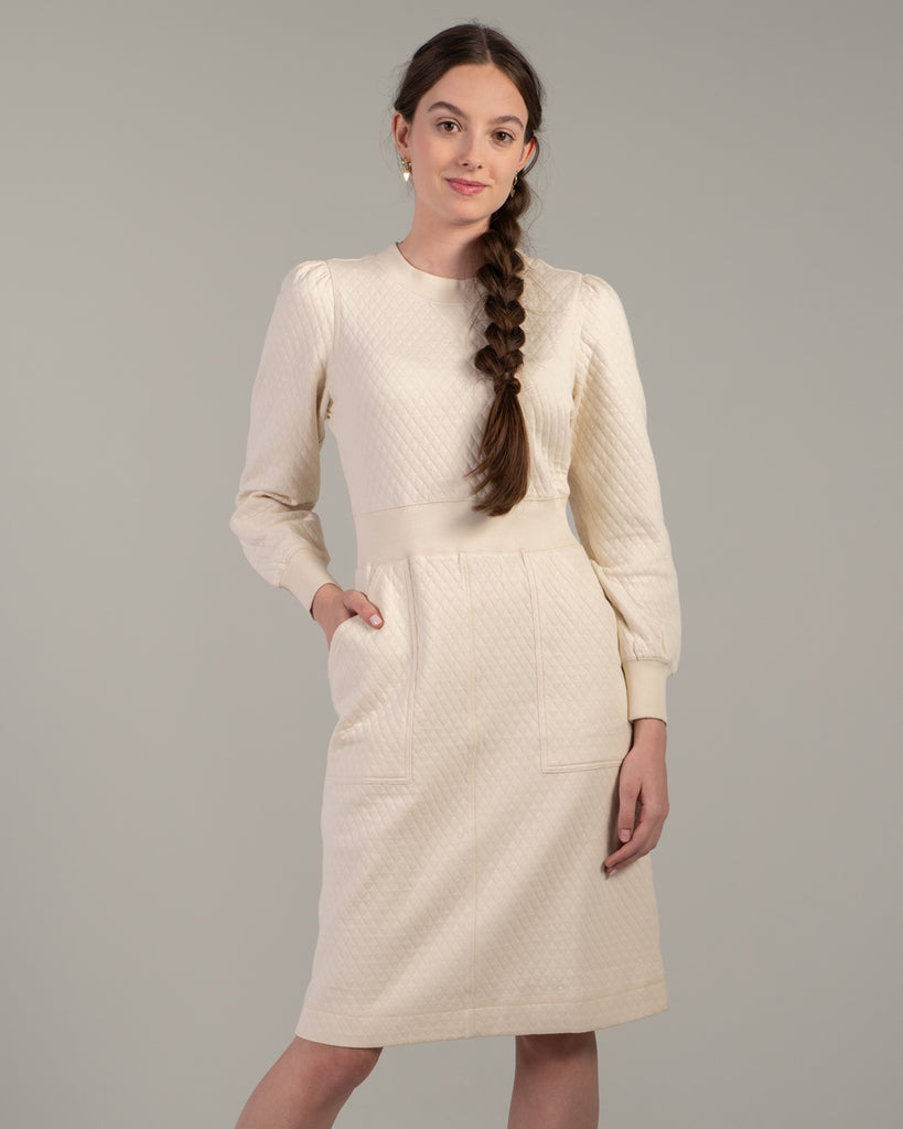 Woman in a white long sleeve, knee-length quilted dress