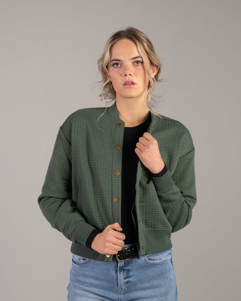 Woman in a green quilted long sleeve bomber jacket