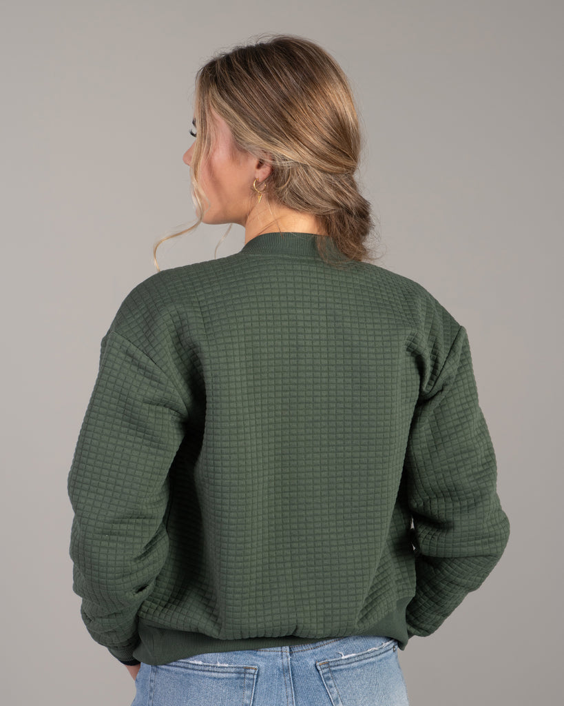 Woman in a green quilted long sleeve bomber jacket