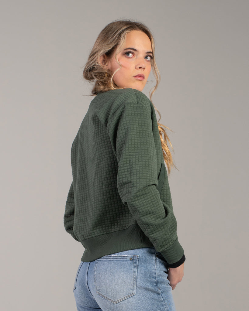 Woman in a green quilted long sleeve bomber jacket