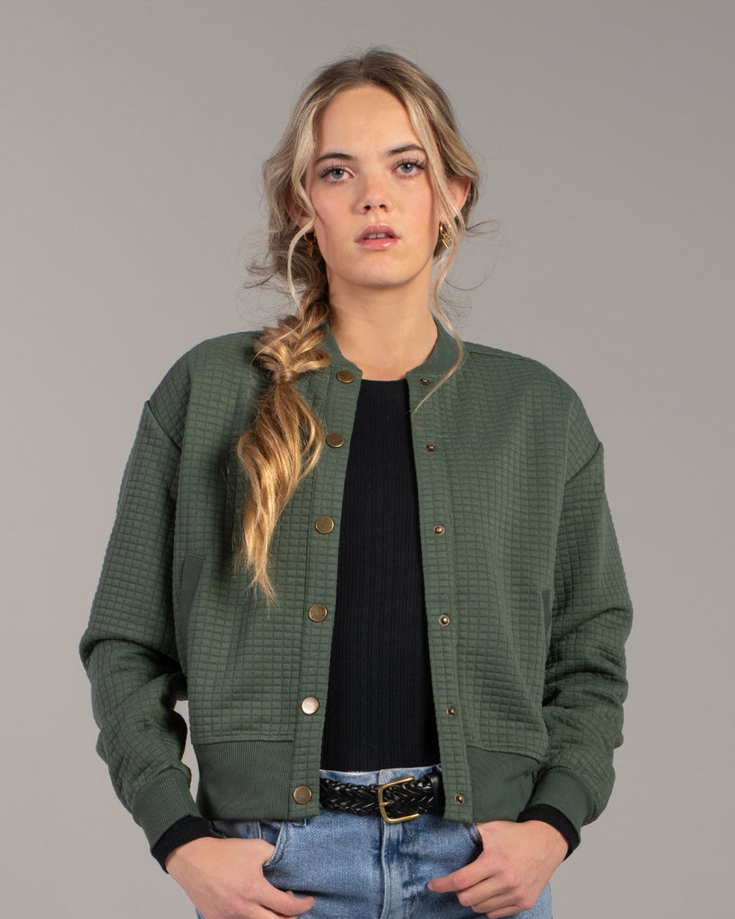 Woman in a green quilted long sleeve bomber jacket