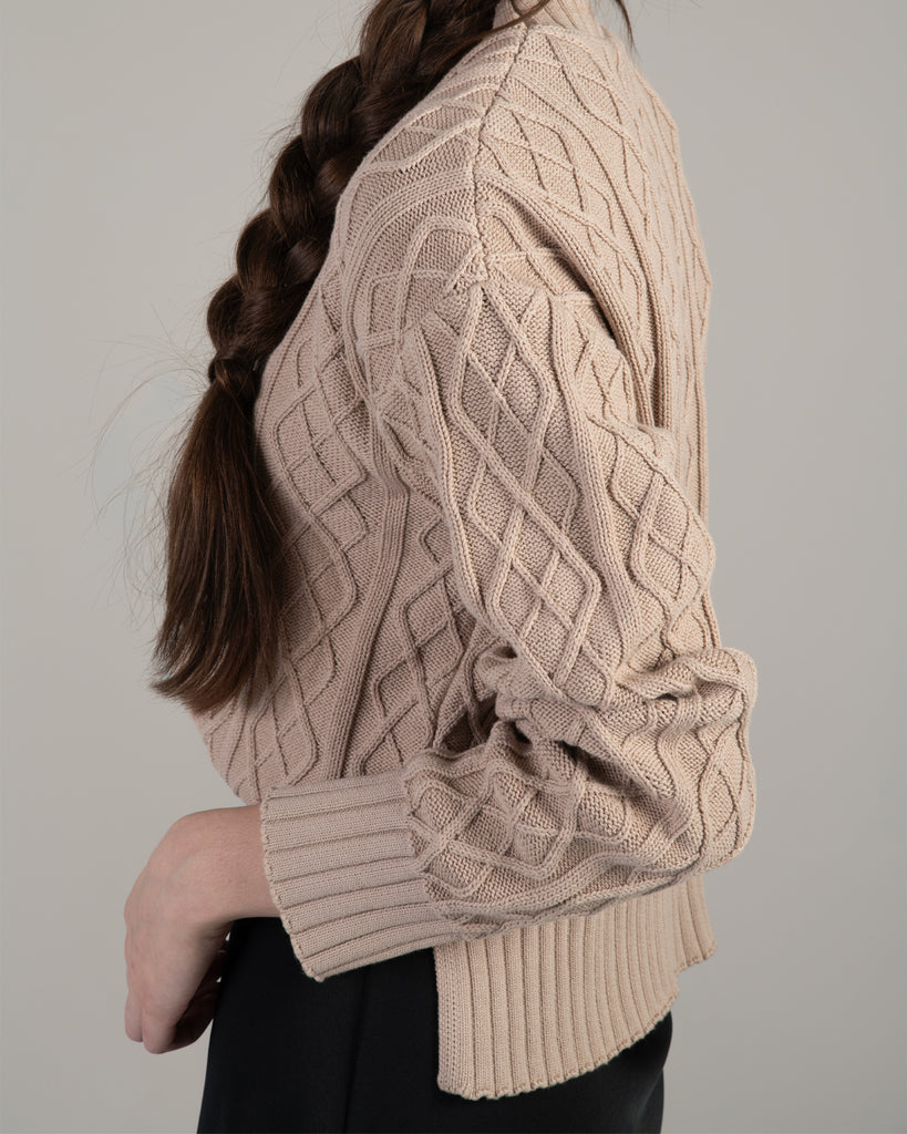 Woman in a tan cable knit long sleeve sweater