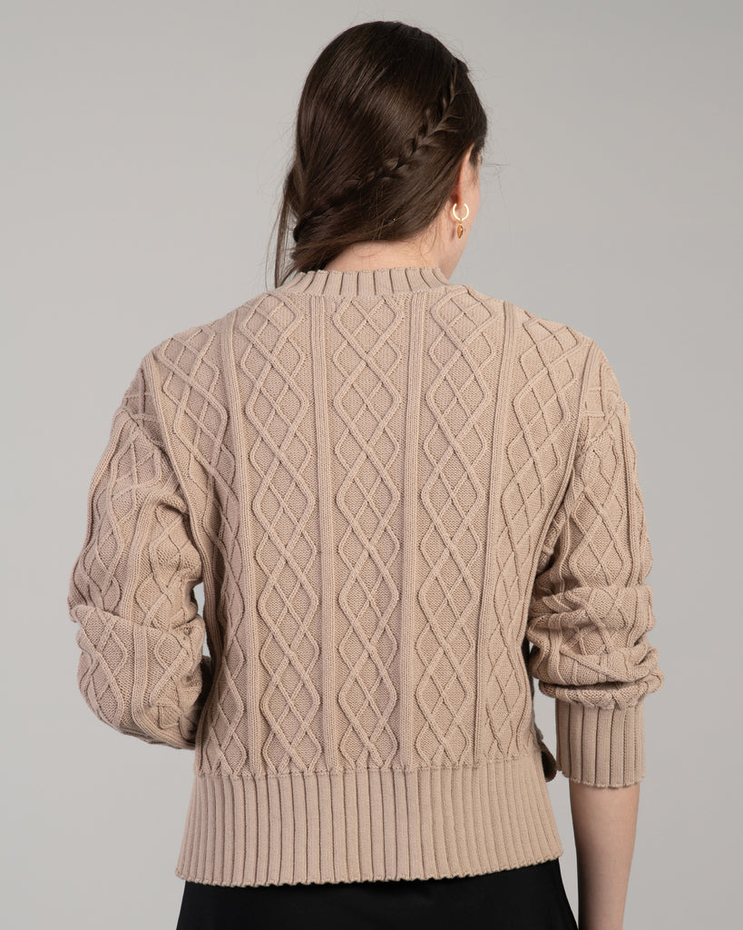 Woman in a tan cable knit long sleeve sweater