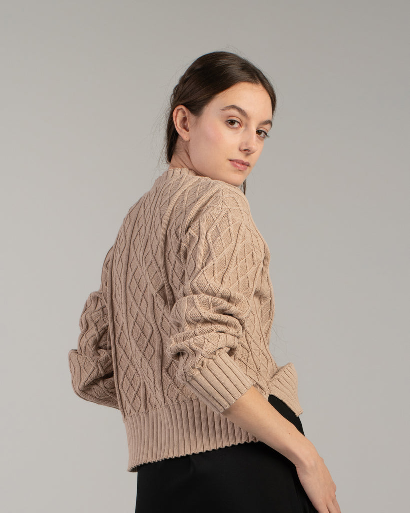 Woman in a tan cable knit long sleeve sweater