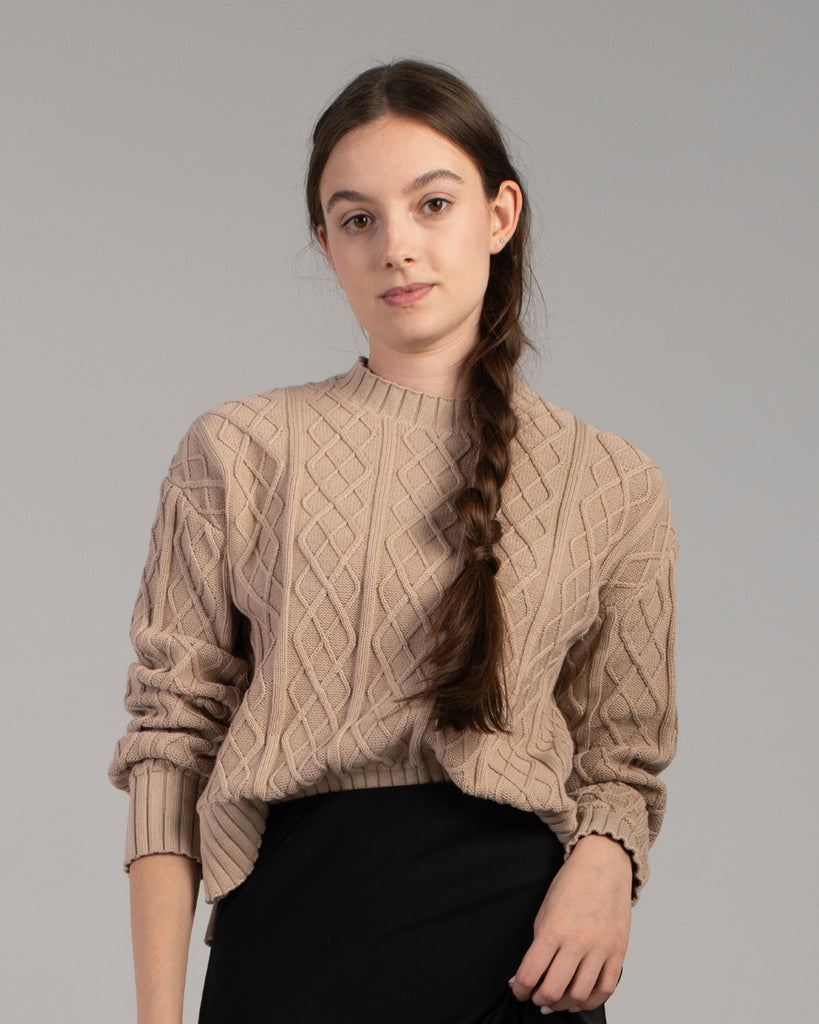 Woman in a tan cable knit long sleeve sweater