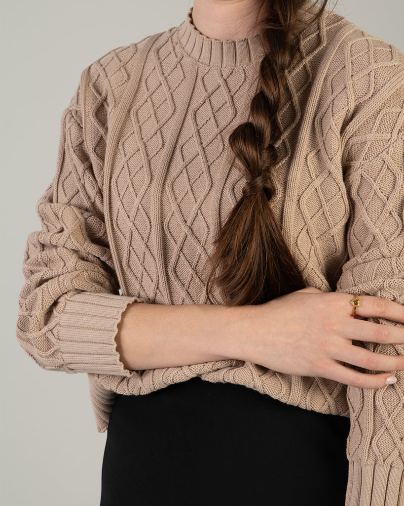 Woman in a tan cable knit long sleeve sweater