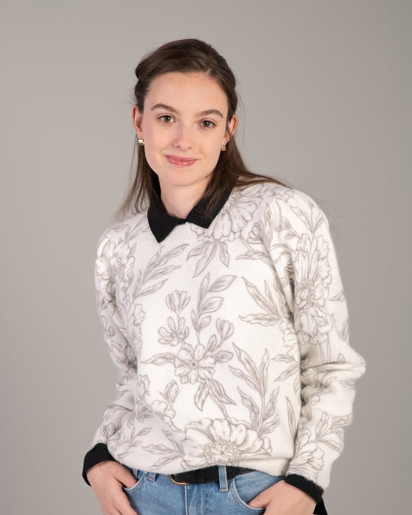 Woman in a white with black floral print sweater