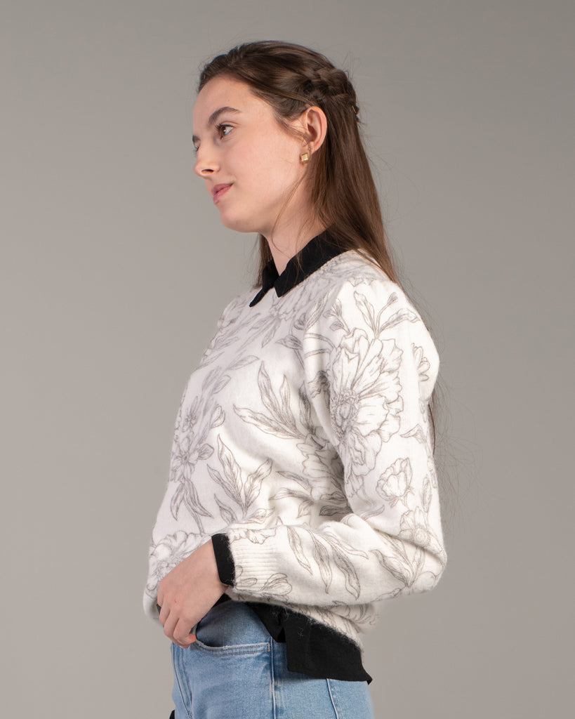 Woman in a white with black floral print sweater