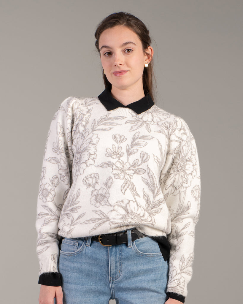 Woman in a white with black floral print sweater