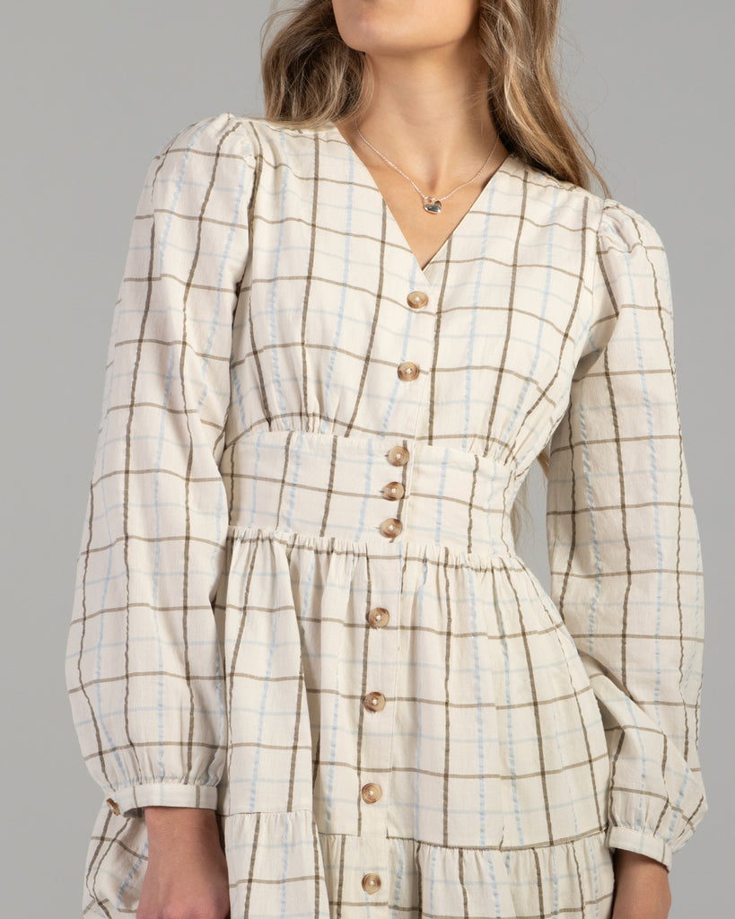 Woman in a beige plaid long sleeve midi length dress