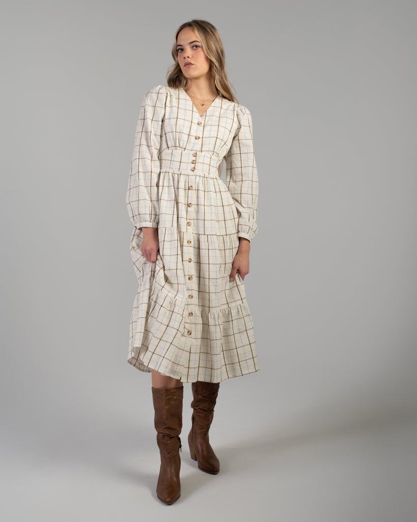 Woman in a beige plaid long sleeve midi length dress