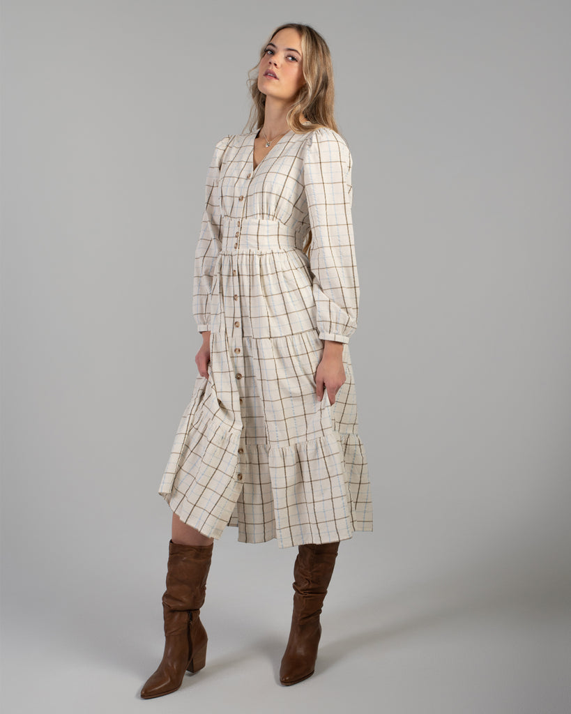 Woman in a beige plaid long sleeve midi length dress