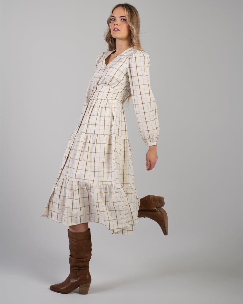 Woman in a beige plaid long sleeve midi length dress