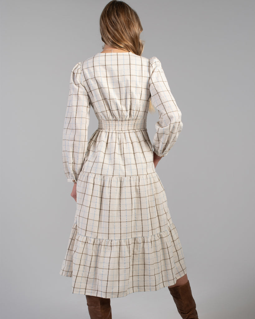 Woman in a beige plaid long sleeve midi length dress