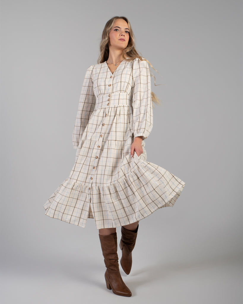 Woman in a beige plaid long sleeve midi length dress