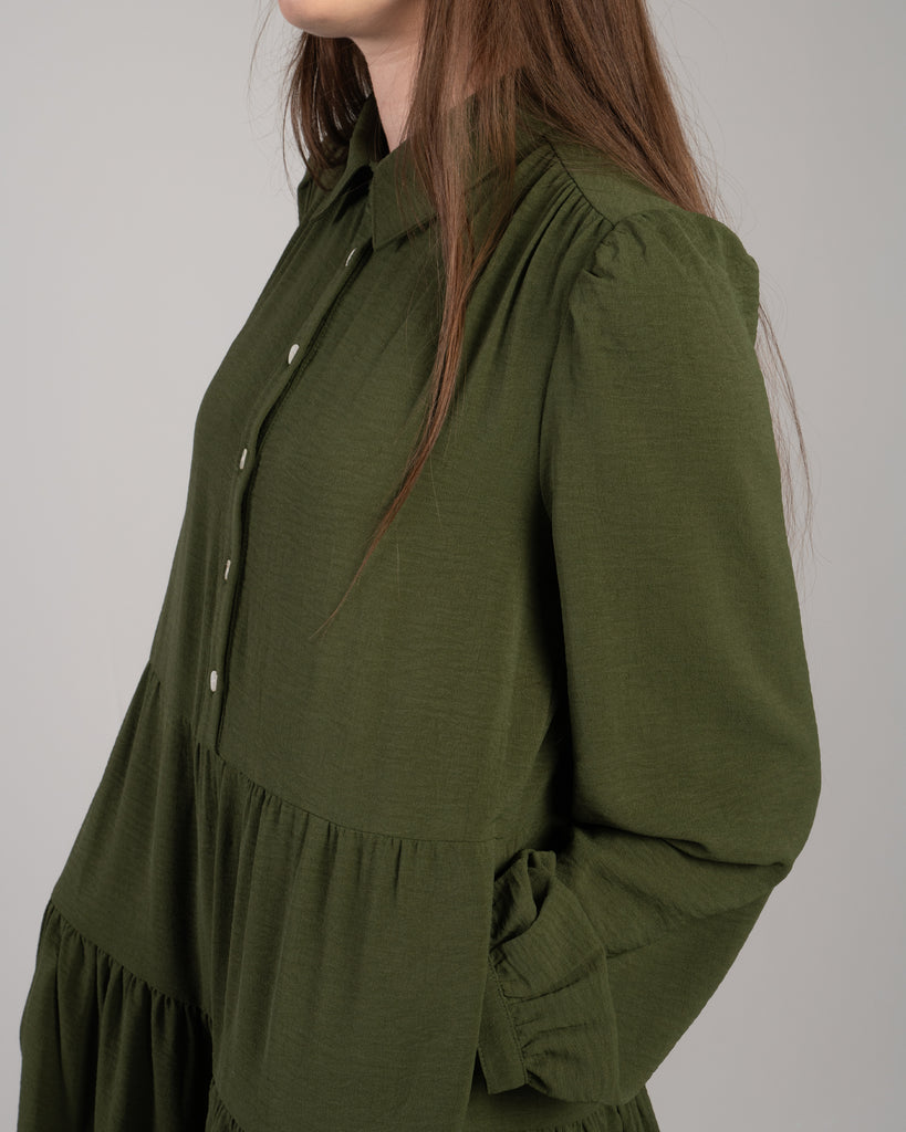 Up-close image of model in a green long sleeve dress with a collar and buttons down front.