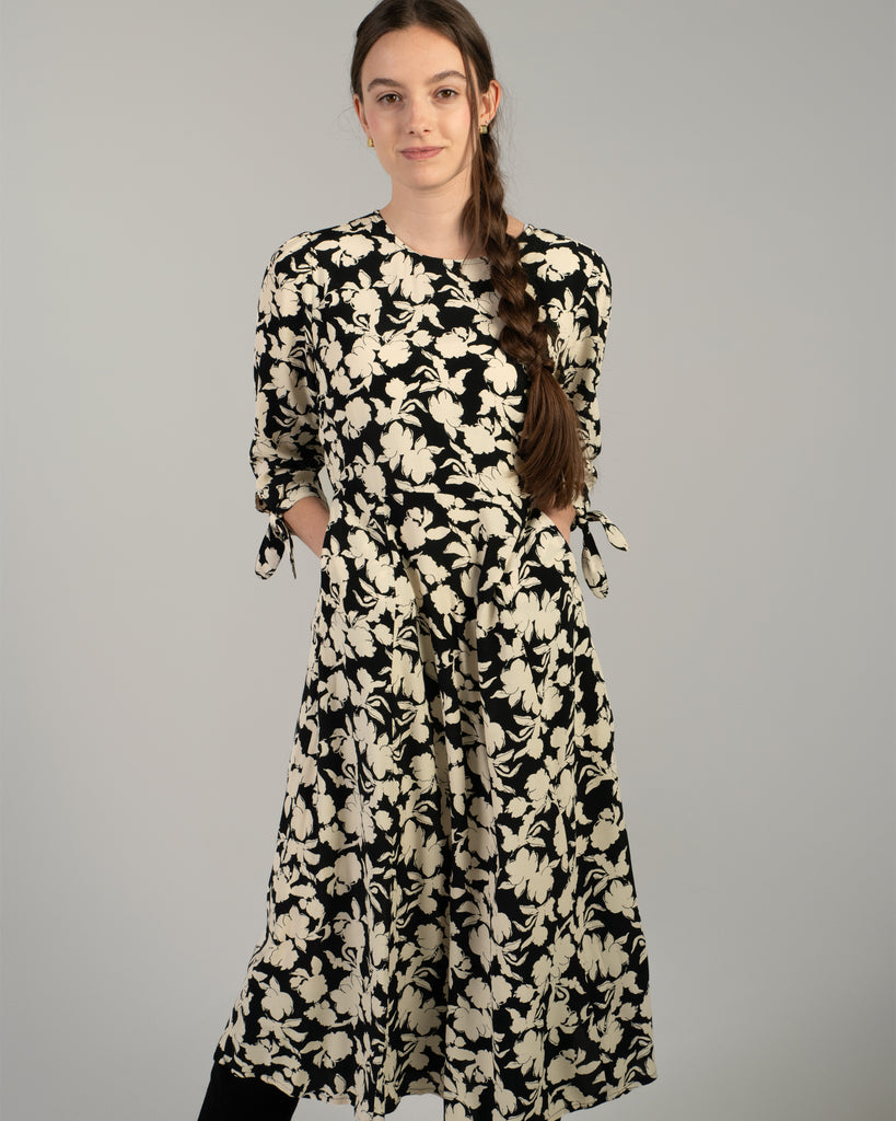 Woman in a black and white floral print, 3/4 sleeve midi length dress