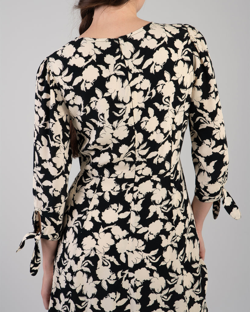 Woman in a black and white floral print, 3/4 sleeve midi length dress