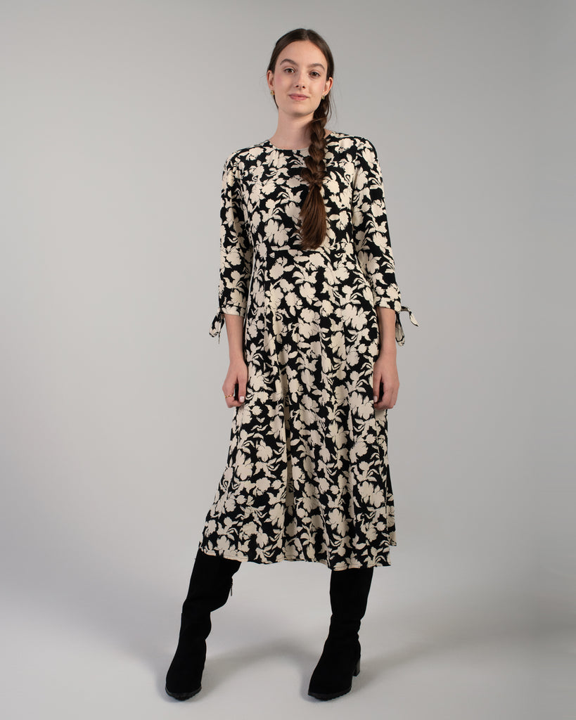 Woman in a black and white floral print, 3/4 sleeve midi length dress