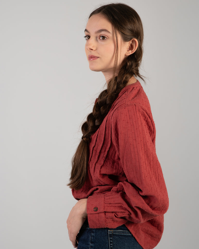 Woman in a red long sleeve blouse with dotted swiss detailing