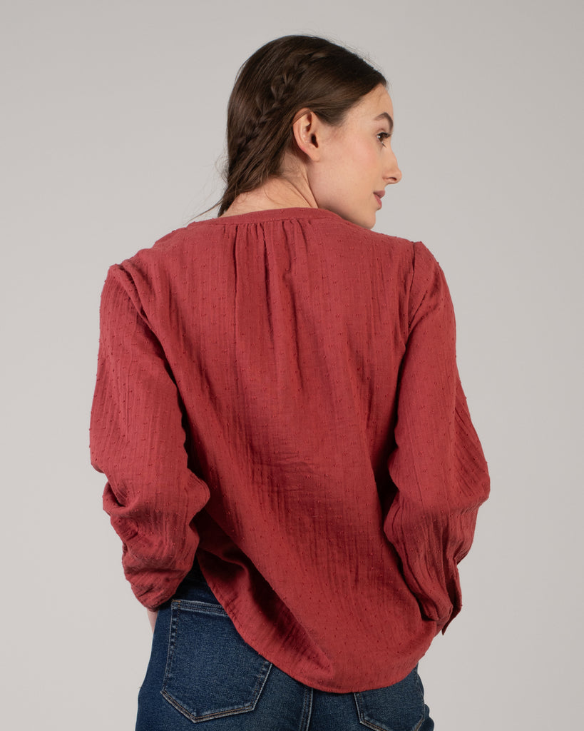 Woman in a red long sleeve blouse with dotted swiss detailing