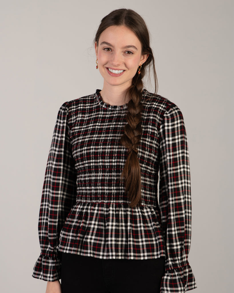 Woman in a black, white and red plaid, long sleeve peplum blouse