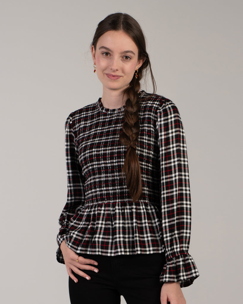 Woman in a black, white and red plaid, long sleeve peplum blouse