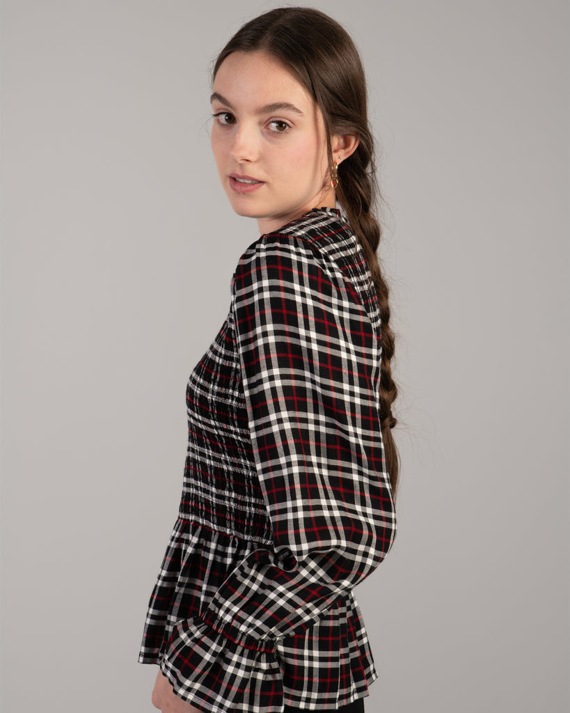 Woman in a black, white and red plaid, long sleeve peplum blouse