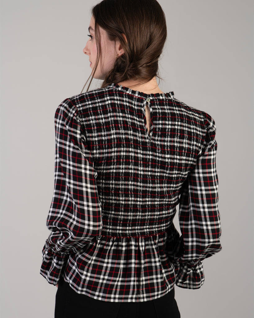 Woman in a black, white and red plaid, long sleeve peplum blouse