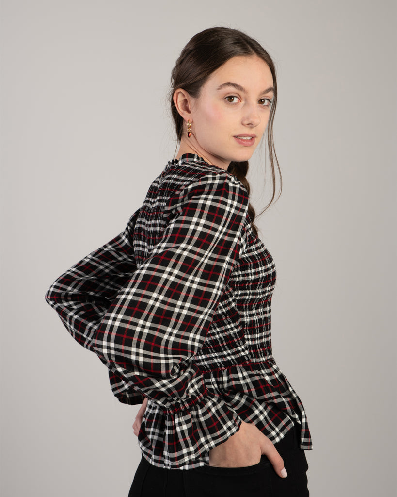 Woman in a black, white and red plaid, long sleeve peplum blouse