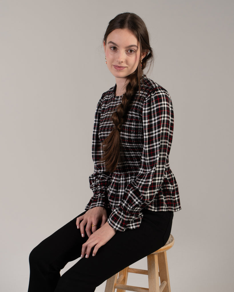 Woman in a black, white and red plaid, long sleeve peplum blouse