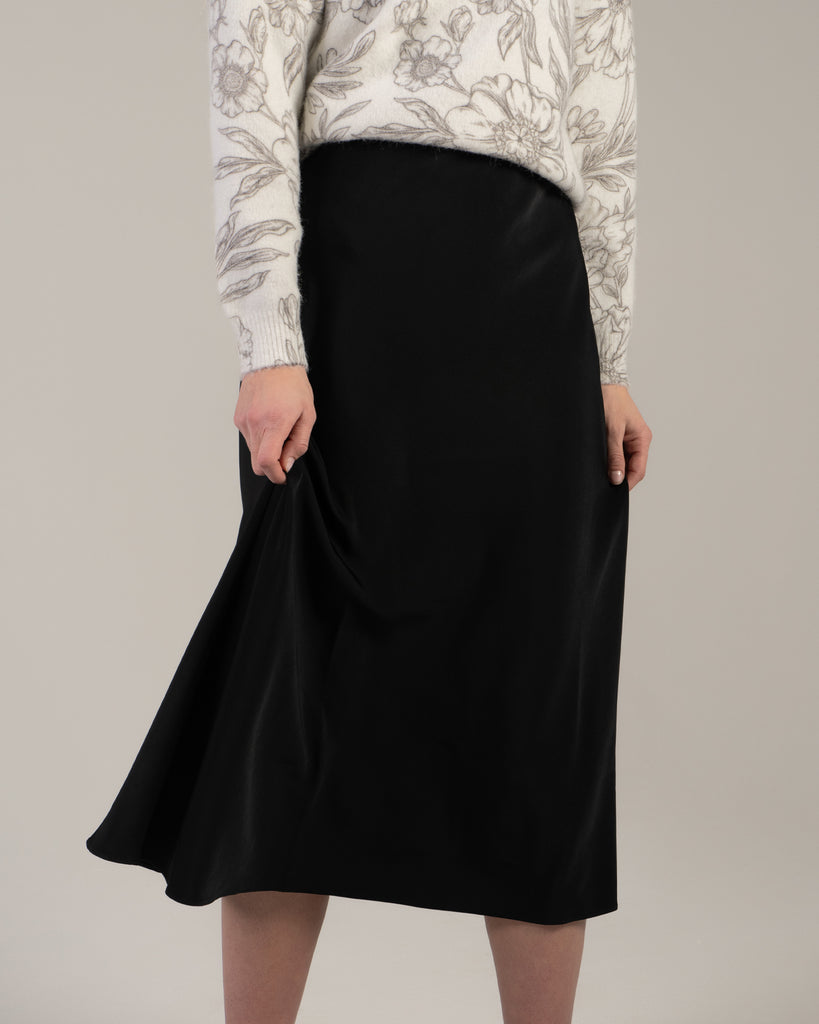 Woman in a black midi length slip skirt