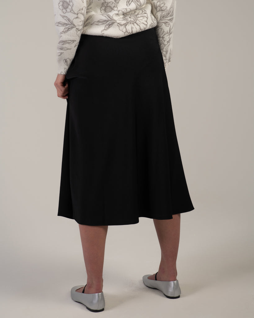 Woman in a black midi length slip skirt