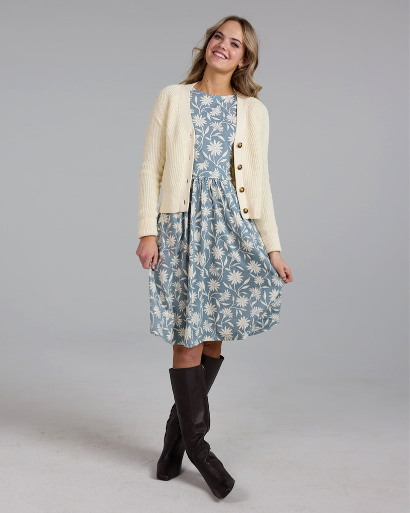 Model wearing a blue and white floral print, long sleeve, knee-length knit dress with pockets.