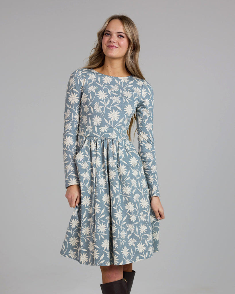 Model wearing a blue and white floral print, long sleeve, knee-length knit dress with pockets.