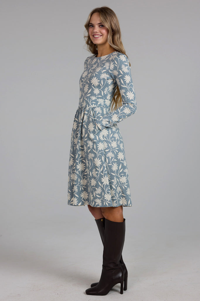 Model wearing a blue and white floral print, long sleeve, knee-length knit dress with pockets.