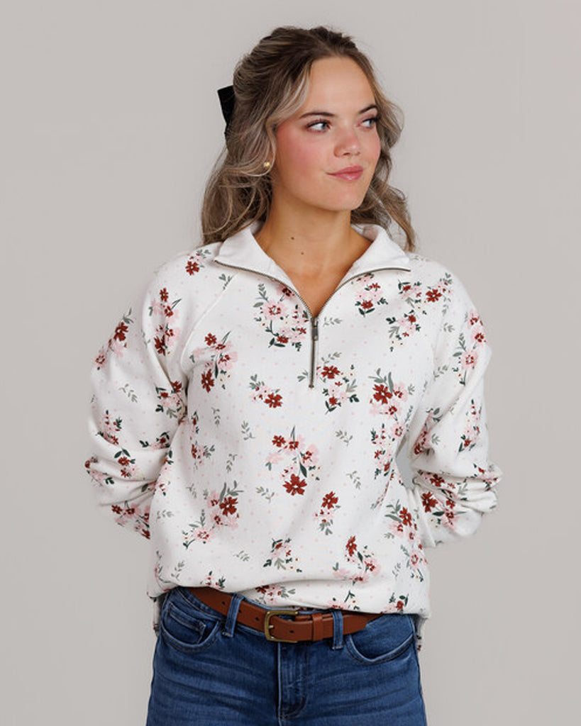 Model wearing a white with pink and red flowers, long sleeve, quarter zip sweatshirt.