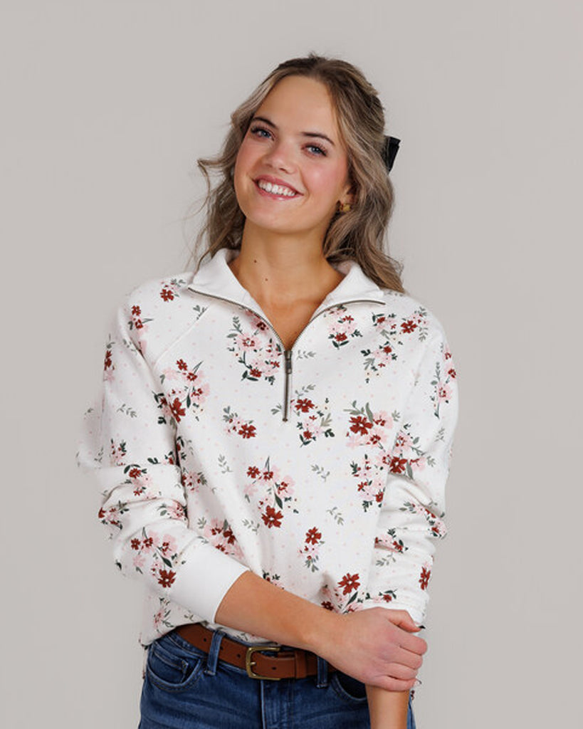 Model wearing a white with pink and red flowers, long sleeve, quarter zip sweatshirt.