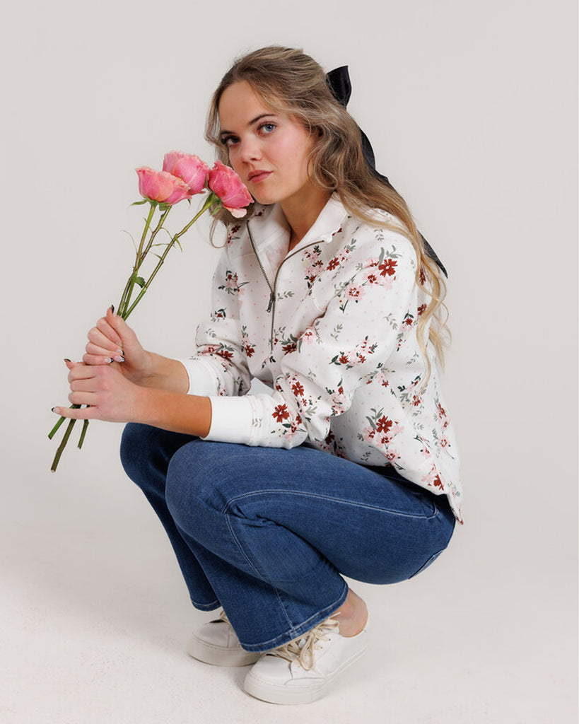 Model wearing a white with pink and red flowers, long sleeve, quarter zip sweatshirt.