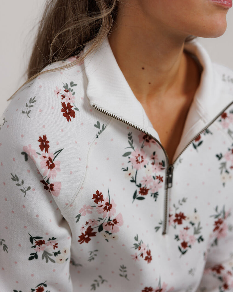 Model wearing a white with pink and red flowers, long sleeve, quarter zip sweatshirt.