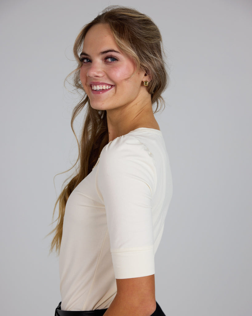 Model wearing a white half sleeve scoop neck henley top.