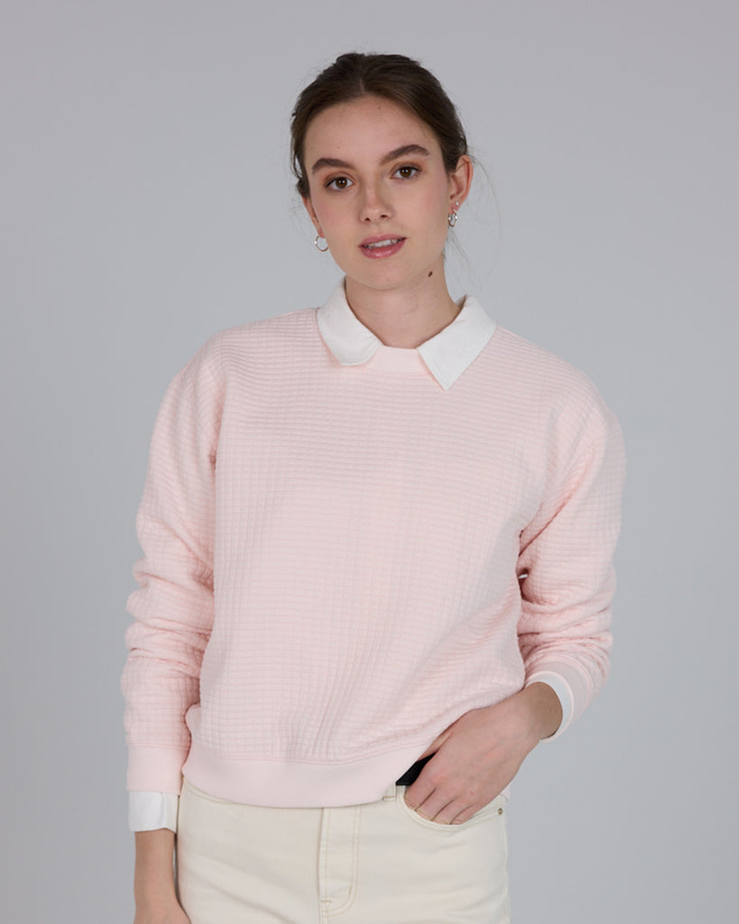 Model wearing a light pink, long sleeve, crew neck pullover sweater.