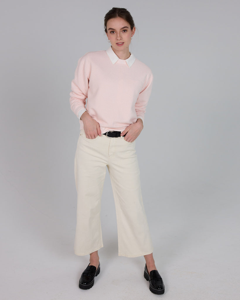 Model wearing a light pink, long sleeve, crew neck pullover sweater.