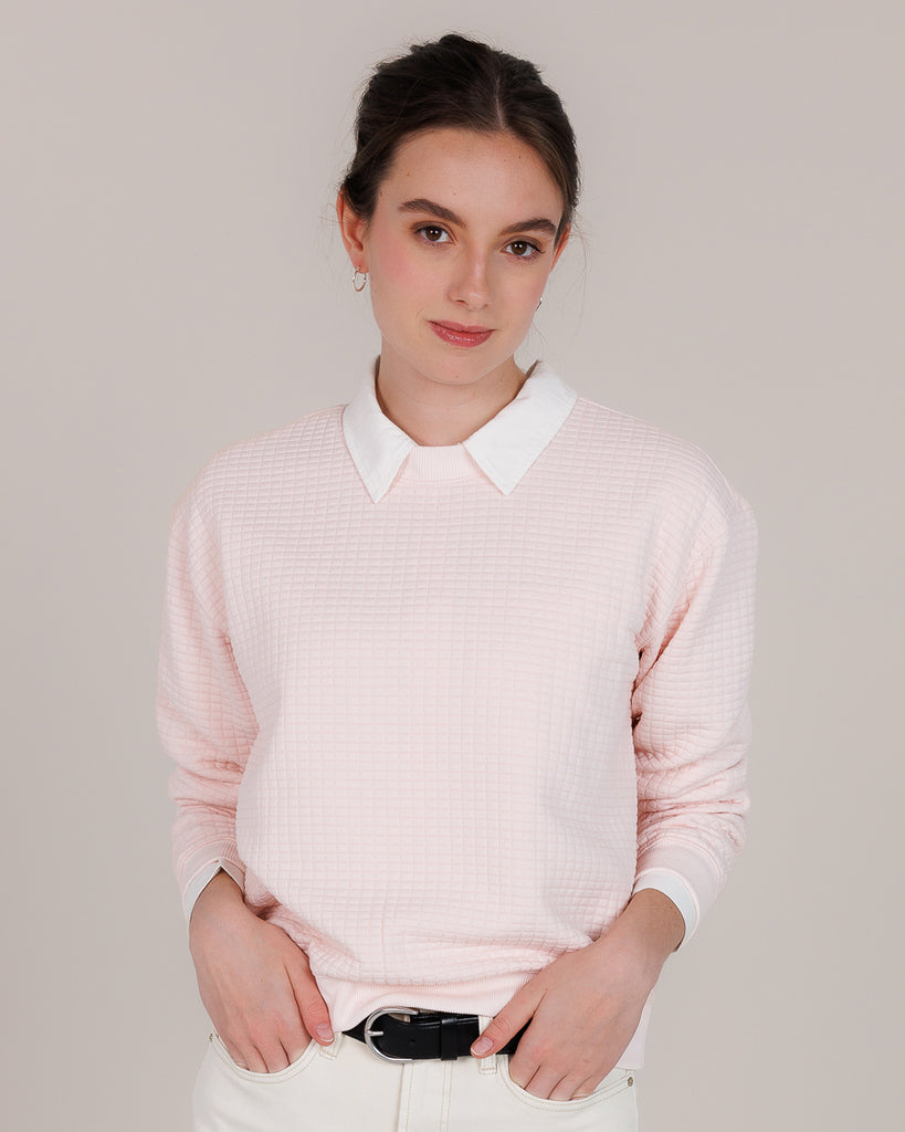 Model wearing a light pink, long sleeve, crew neck pullover sweater.