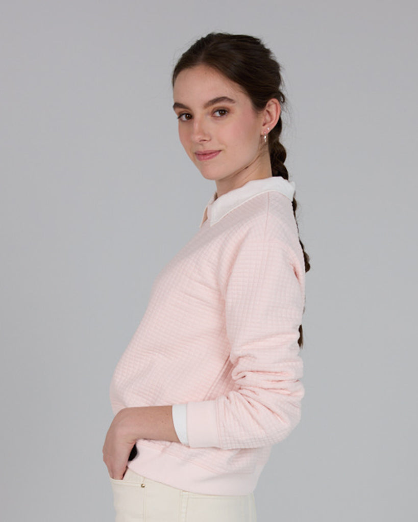 Model wearing a light pink, long sleeve, crew neck pullover sweater.